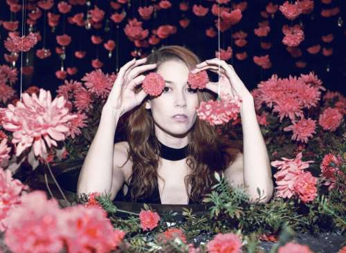 Woman With Red Hair Half Hides Behind Red Flowers Photo