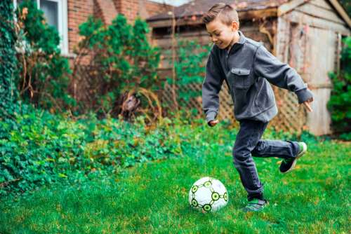 Young Boy Kicking Ball Photo