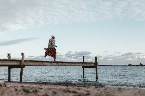 Young Woman In Autumn Clothing Running Across Dock Photo