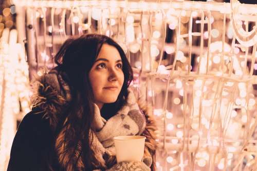 Christmas lights and a girl holding a coffee