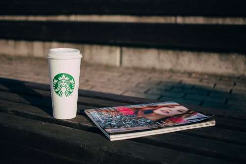 Coffee and a magazine on a bench
