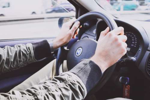Male hands on a car steering wheel