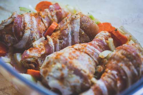 Raw chicken legs wrapped in bacon
