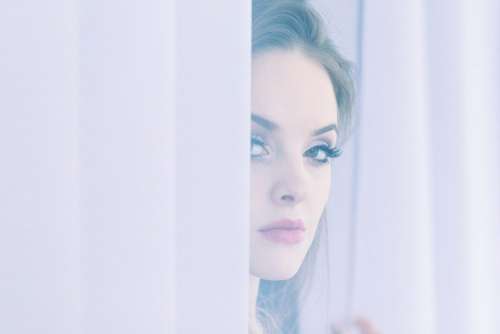 A woman peering through curtains