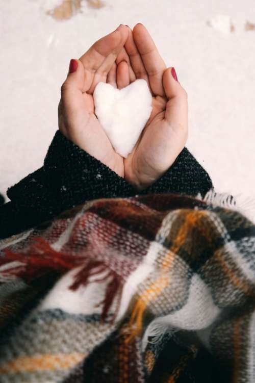 Hand holding White Snow in Heart shape free photo