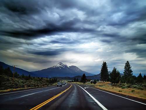 Highway Road into the mountains under heavy clouds free photo