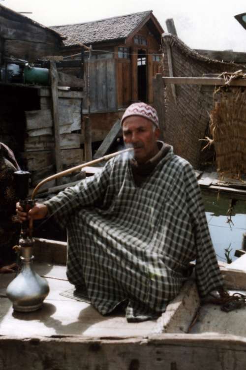 Kashmiri man smoking a traditional hookah pipe in Srinagar, Kashmir, India free photo