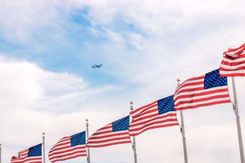 Plane flying above a bunch of USA Flags free photo