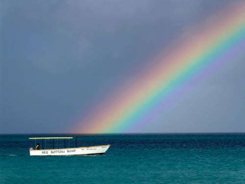 Rainbow over the ocean with a boat in Jamaica free photo