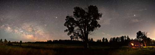 Stars and the Milky way over the night landscape with cabin and tree free photo