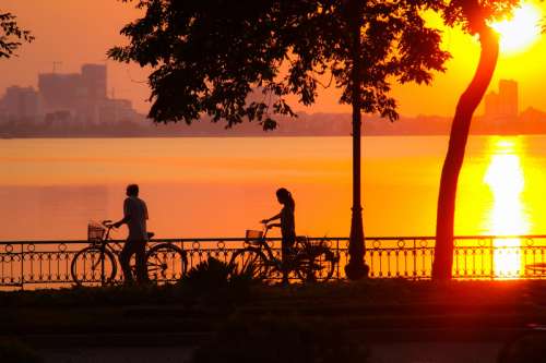 Sunset and 2 cyclists in Hanoi, Vietnam free photo
