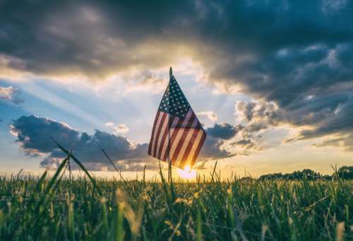 Sunset beyond the American Flag celebrating 4th of July Independence Day free photo
