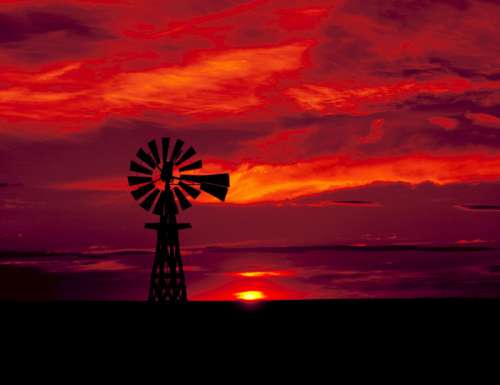 Windmill in the landscape with red skies in Texas free photo