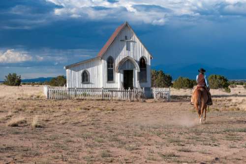 Women riding horse near a small church in Santa Fe, New Mexico free photo