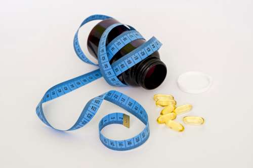 Yellow Pills coming out of bottle with measuring tape free photo