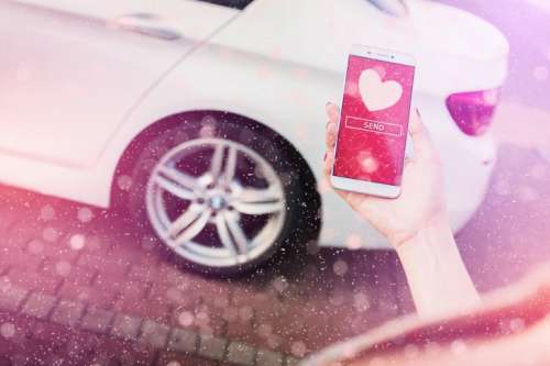 Woman’s hand holding a smartphone. On display are hearts of love. Valentine’s day concept. Sending love
