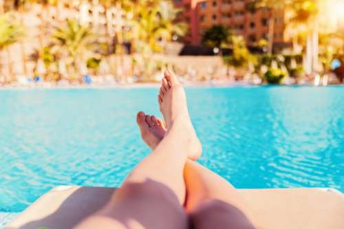 Woman’s legs resting by the pools edge