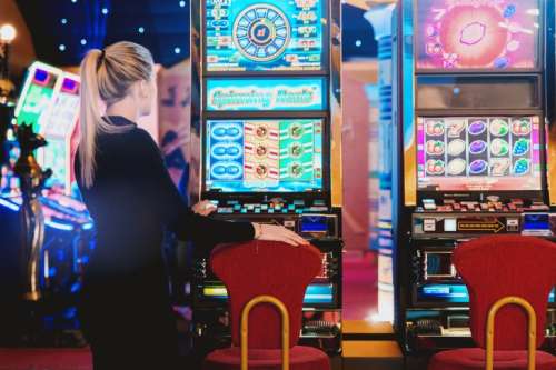 Woman is ready to play at slot machine in casino