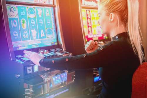 Young woman playing at slot machine in casino. She’s lucky