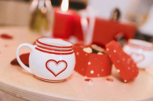Valentines cup with symbol of love on wooden table. Celebration of Valentine’s Day.