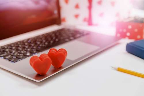Couple red hearts on laptop on white table in office. Online dating.
