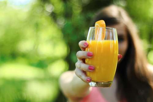 A girl holding a glass with orange juice