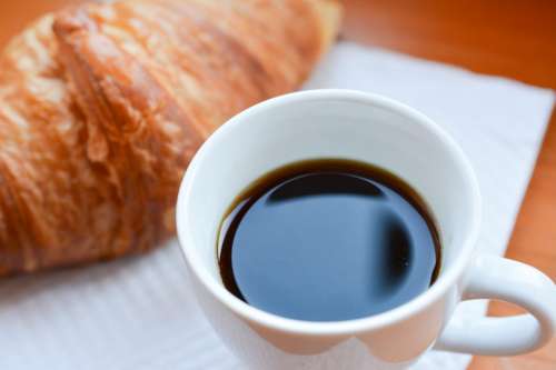 Cup of black coffee with croisssant close up