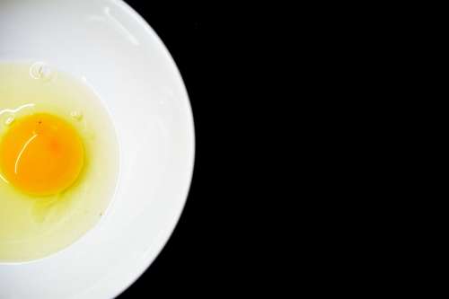 Fresh egg in white bowl on black background