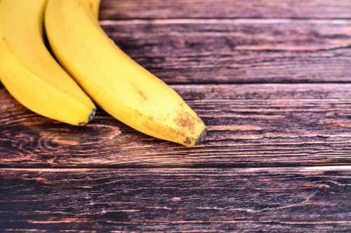Two bananas on wooden background