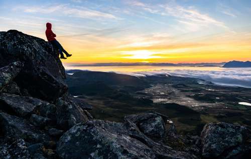 Young Man Watching the Sunrise From Top of the Mountain