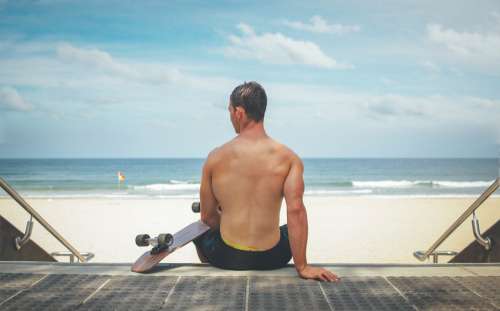 Man Sitting Back Skateboard Steps Beach Sand