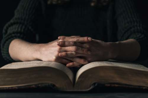 Hands Resting On Open Book Photo