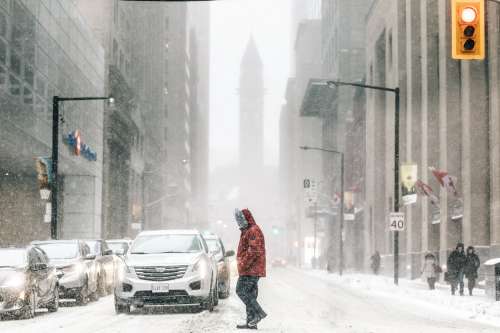 Man In Red Parka Crossing In Front Of Traffic Photo