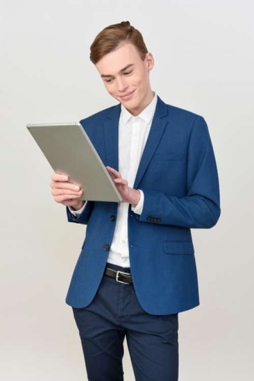 Man In Suit With Light Smile On The Face Looking At The Tablet