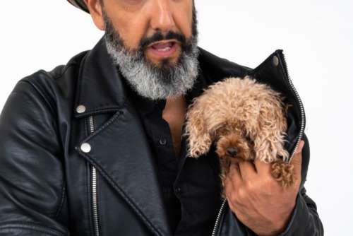 Mature Man Holding A Puppy Under His Jacket