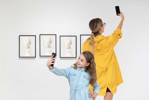 Mother And Daughter Making Selfies In Art Gallery