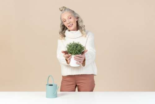 Smiling Old Woman Holding Plant In Pot