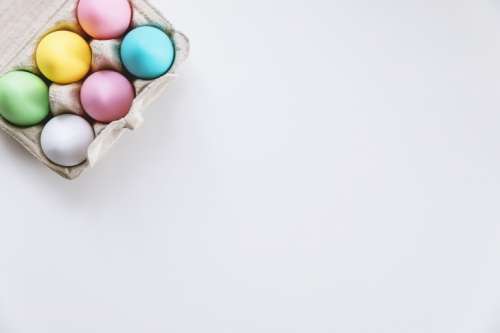 Close-up view of colorful eggs in egg box on white background