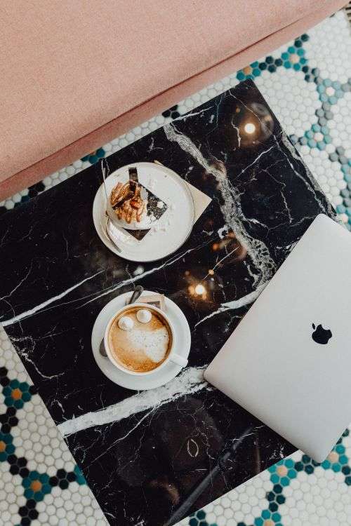Laptop, coffee and cake with meringue and whipped cream on black marble