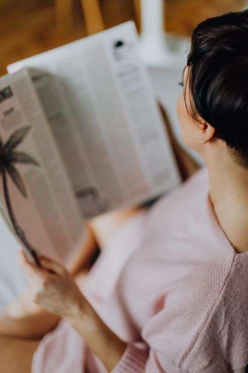 A woman with short dark hair reads a newspaper