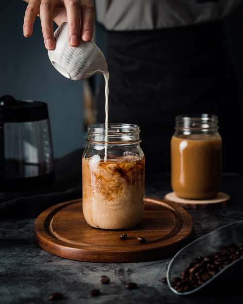 Pouring milk in a jar with coffee