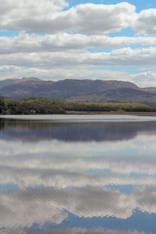 Calm Waters Reflect Puffy White Clouds And Blue Skies Photo