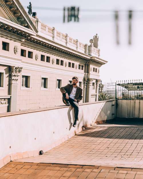 Man Sit Casually On Roof Ledge Photo