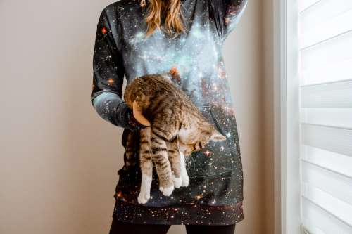 Woman Wearing Hoodie Holds Cat In One Hand Photo
