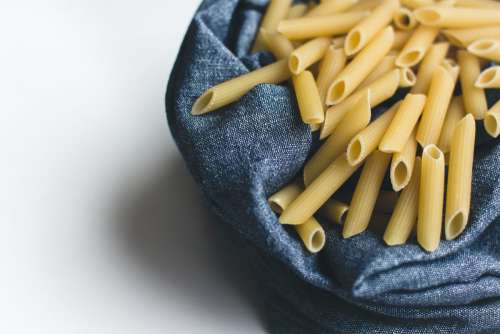Pasta penne in a blue cotton tablecloth