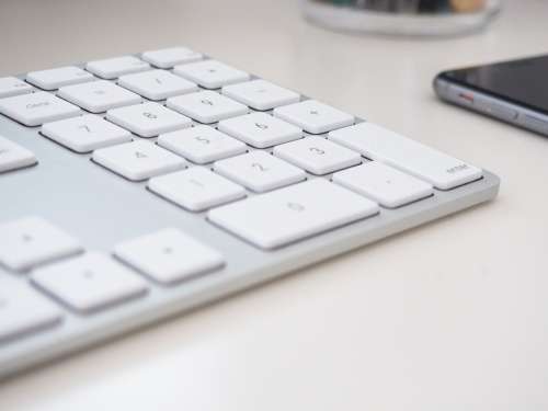 Keyboard and Phone on White Desk