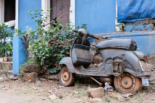 Abandoned Scooter in Front of a Blue House