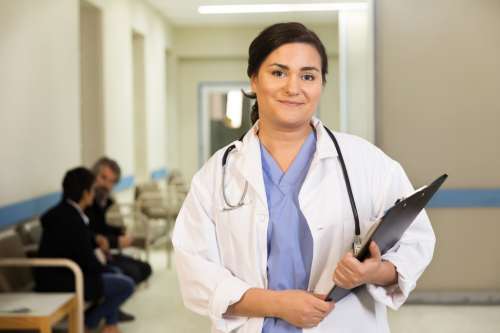 A Doctor Smiles While Holding Her Clipboard Photo