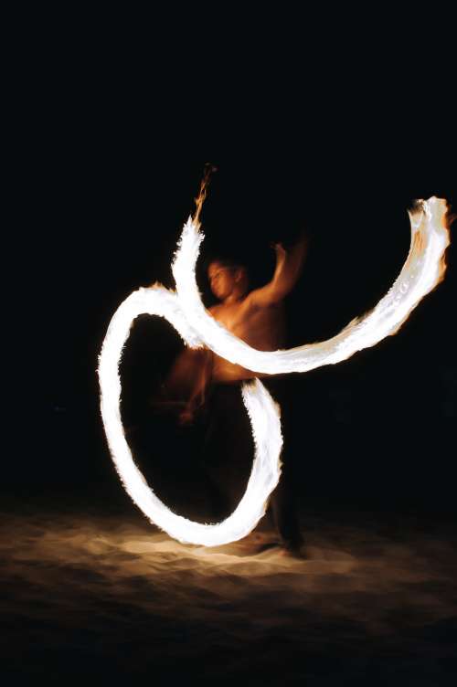 A Fire Dancer Cuts Figures Of Eight At Night On A Beach Photo