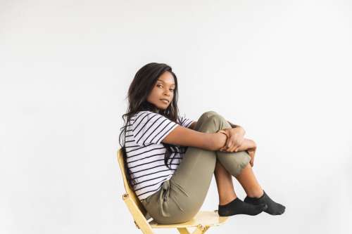 A Model Holds Knee To Chest On Chair Pensively Photo